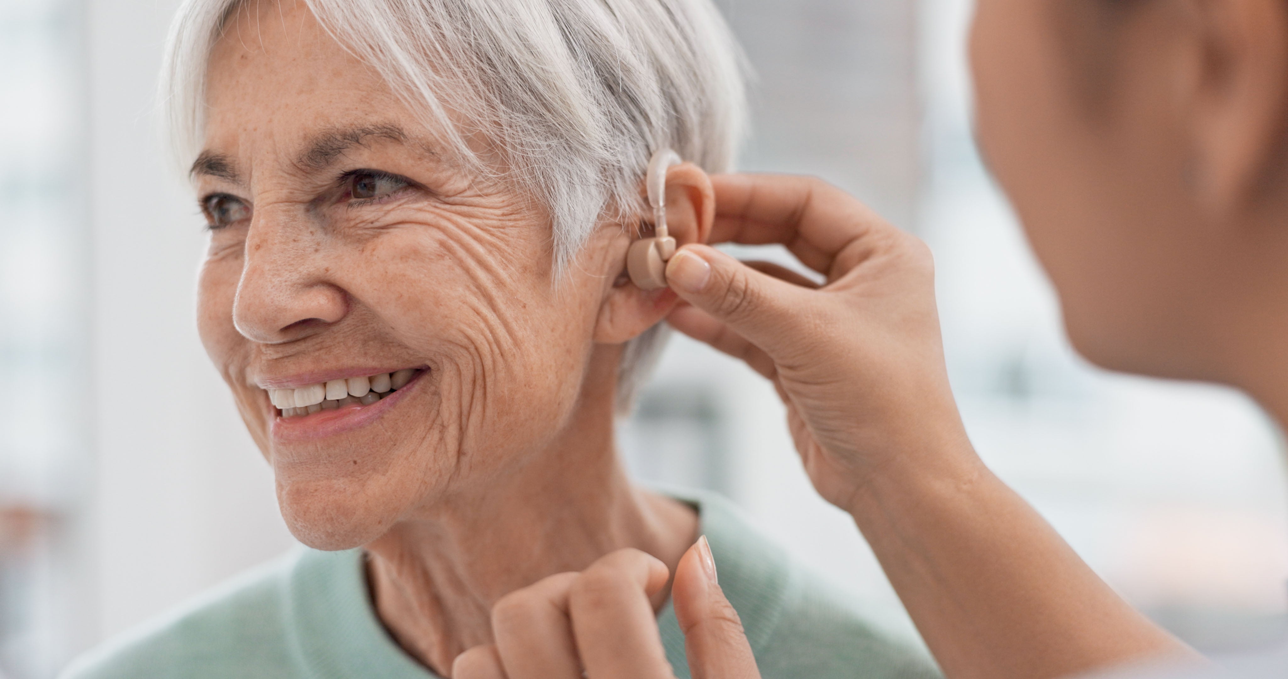 Woman being fit for hearing aid by doctor