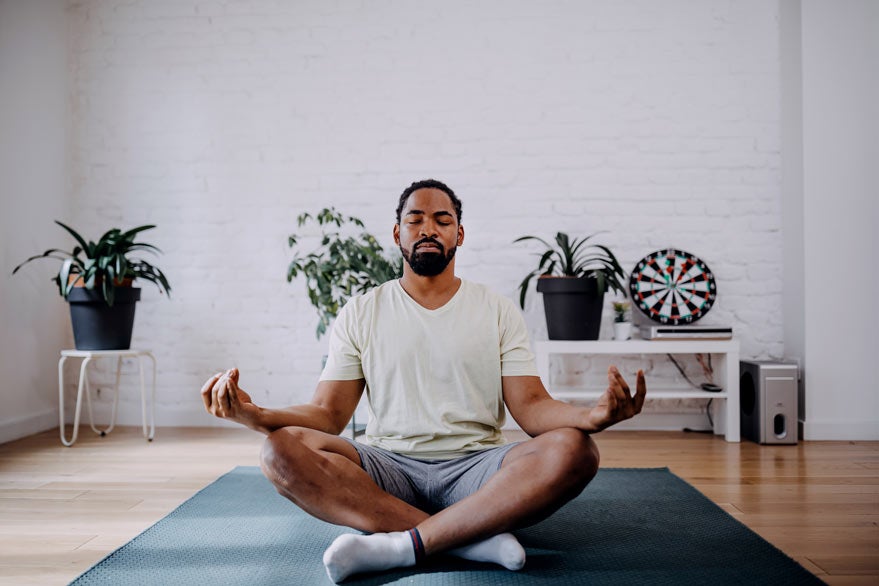 Man meditating at home on a yoga mat
