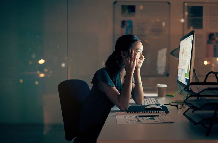 Woman staring at computer screen with glare reflected on her face