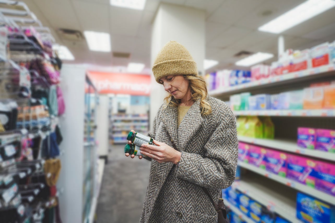 Woman in yellow beanie at drug store buying vitamins