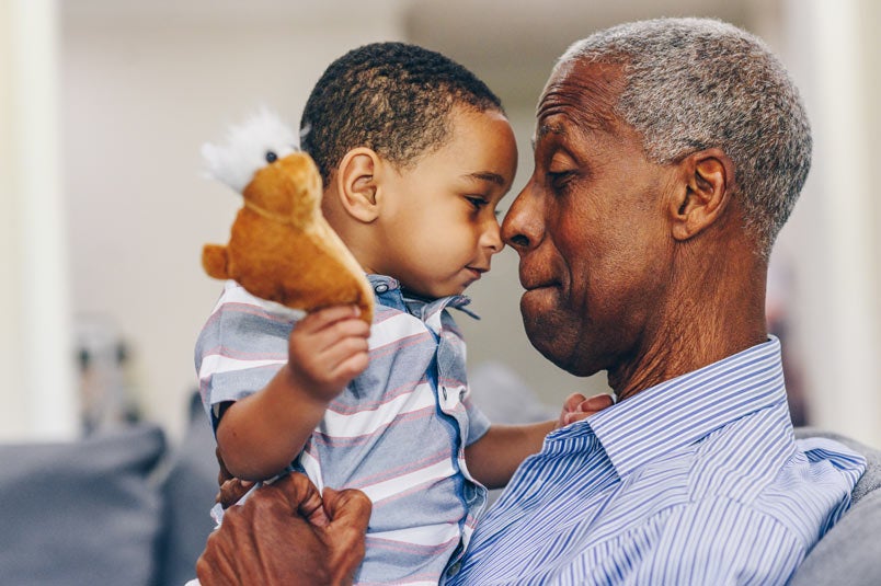 Older man holding up baby boy, face to face 