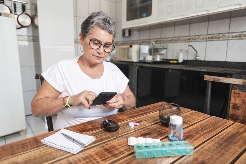 Older woman planning out her diabetes medication at kitchen table