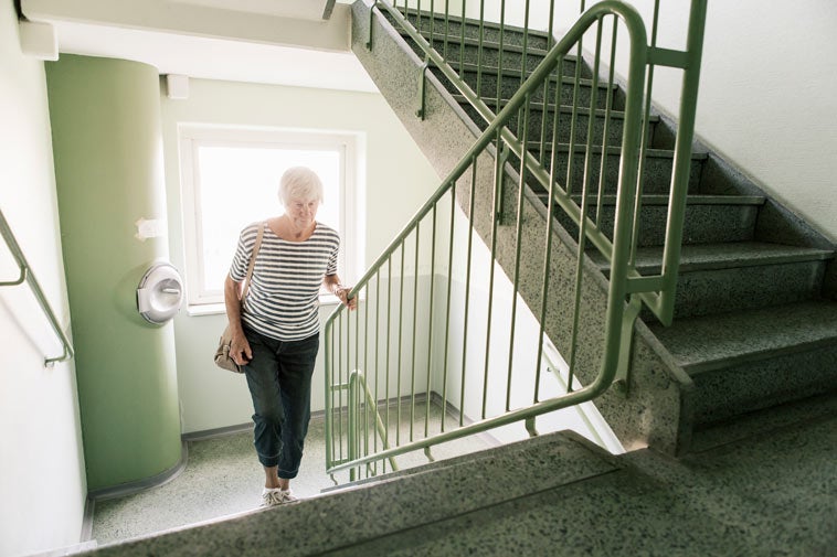 older woman going up the stairs in an apartment building