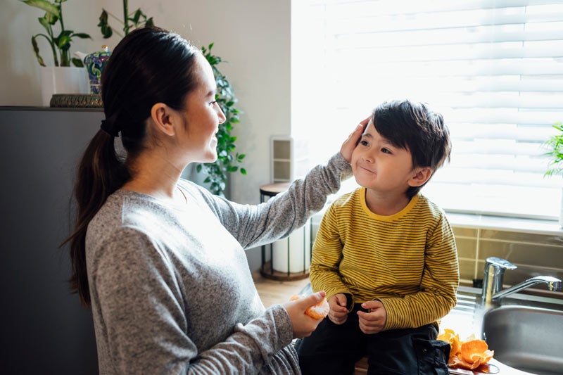 Mother examining son's face sitting on a kitchen counter