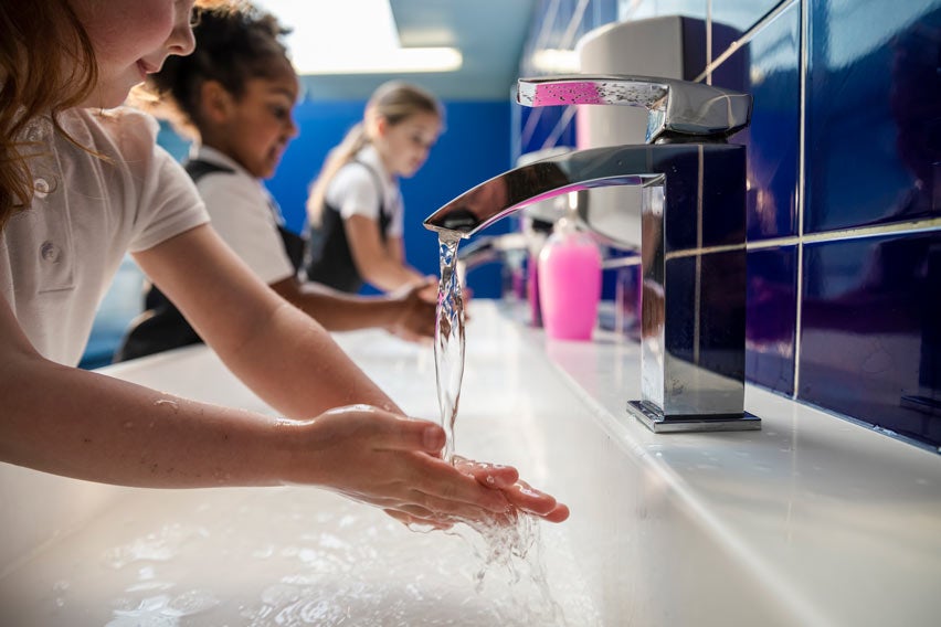 Children washing hands at school bathroom sink