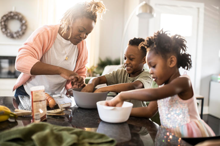 Mother and children mixing ingredients in kitchen